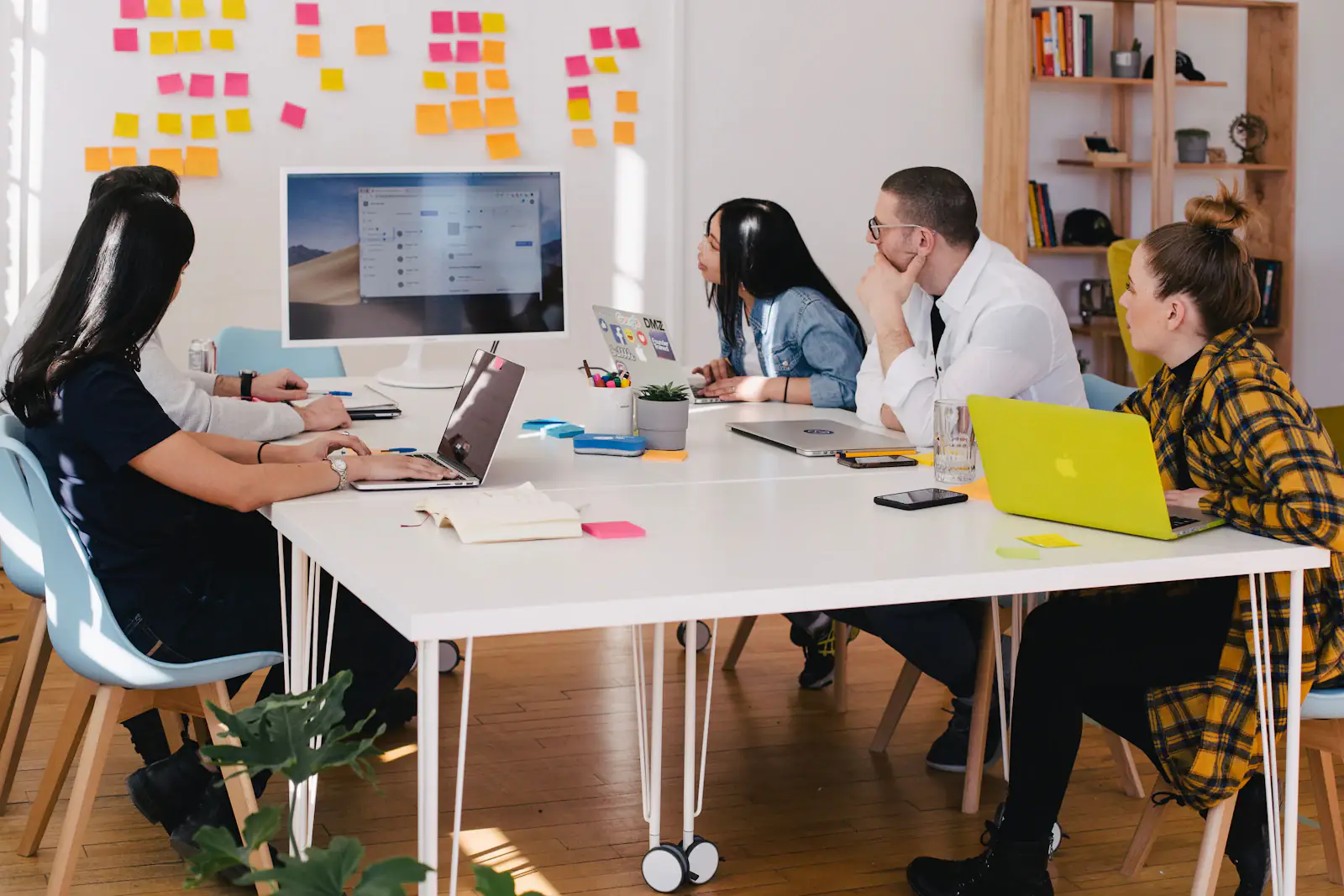 Equipe reunida numa mesa conferindo o sistema aberto num monitor